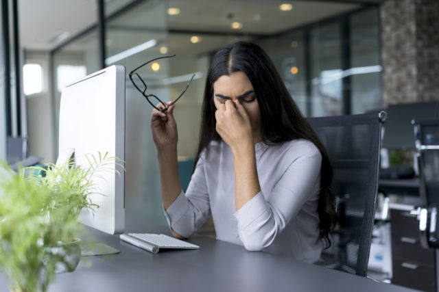 Depressed businesswoman rubbing eyes in office